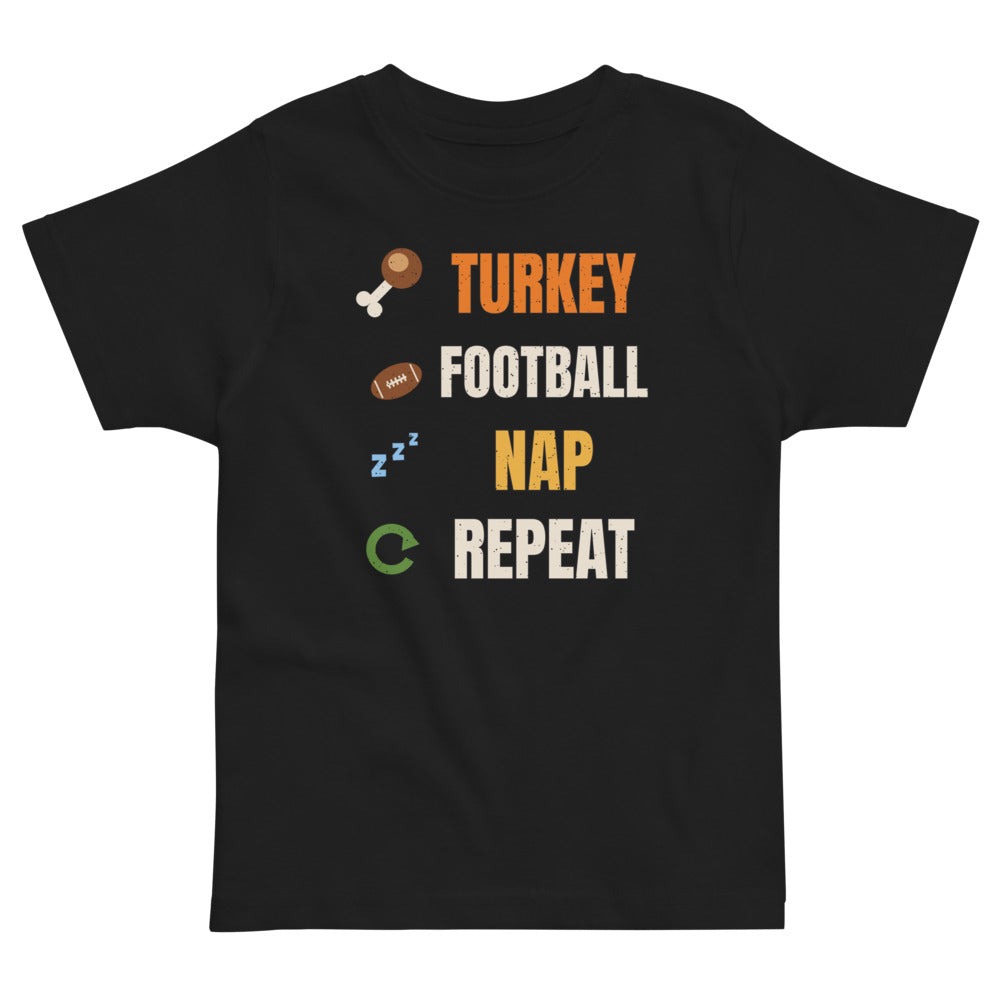 Turkey Football Nap Repeat Toddler Tee in black, mockup of the design printed on the front of the toddler tee