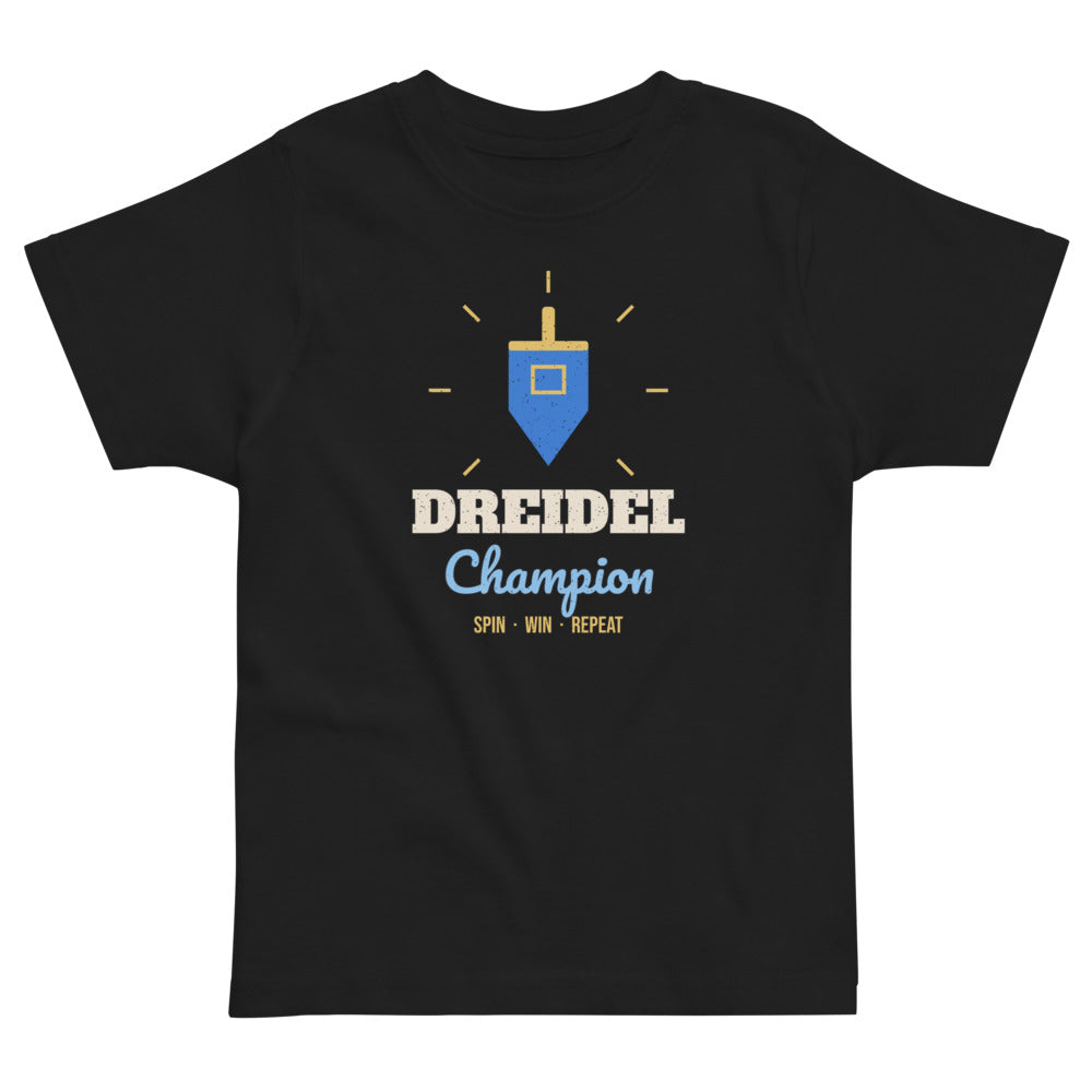 Dreidel Champion Toddler Tee in black, mockup of the design printed on the front of the toddler tee