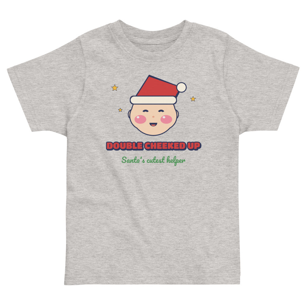 Double Cheeked Up Santa's Cutest Helper Toddler Tee in heather, mockup of the design printed on the front of the toddler tee