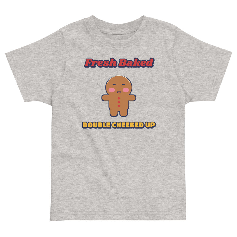 Double Cheeked Up Fresh Baked Gingerbread Toddler Tee in heather, mockup of the design printed on the front of the toddler tee